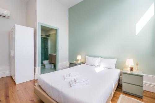 ポルトにあるGuestReady - Porto Home 6の白いベッドルーム(大きな白いベッド1台付)、バスルームが備わります。