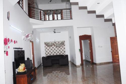 a living room with a couch and a staircase at Shri Sai Baba Homestay - EB Colony - Trichy in Tiruchchirāppalli