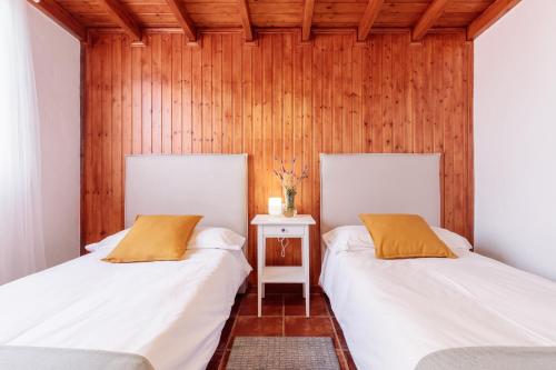 two beds in a room with wooden walls at Casa Buganvillas, reformado in Puntagorda