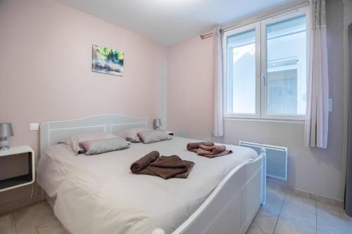 Un dormitorio con una cama blanca con toallas. en Les Perles de Vals - Améthyste, en Vals-les-Bains