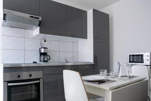 uma cozinha com armários pretos e uma mesa com cadeiras em Les Perles de Vals - Améthyste em Vals-les-Bains