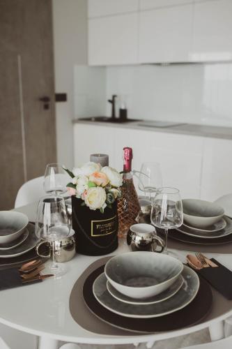 a table with plates and glasses and a vase of flowers at Apartamenty BLUE BALTIC SPA Jacuzzi & Sauna MORZE in Chłopy