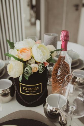 a bottle of wine and a vase of flowers on a table at Apartamenty BLUE BALTIC SPA Jacuzzi & Sauna MORZE in Chłopy