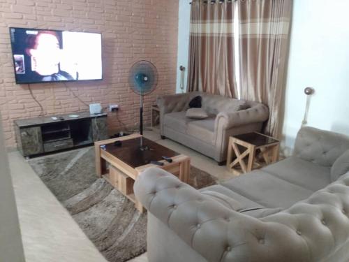 2 bedroom service apartment with full services في Idimu: غرفة معيشة مع كنبتين وتلفزيون