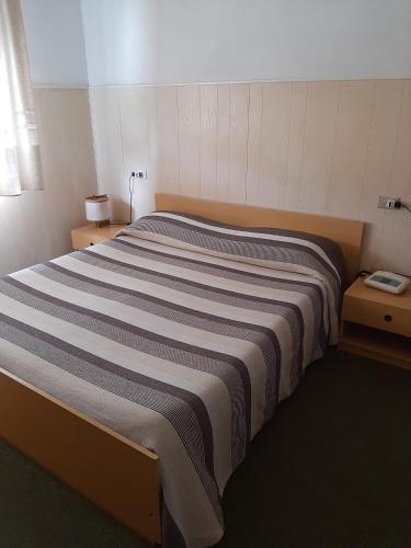 a bedroom with a large bed with a striped blanket at Hotel Cucciolo in Donoratico