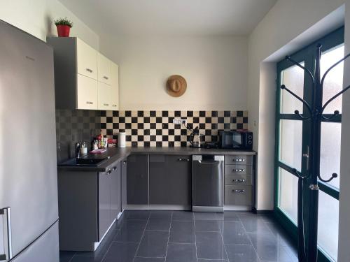 a kitchen with gray cabinets and black and white tiles at Penzion Lednice in Lednice