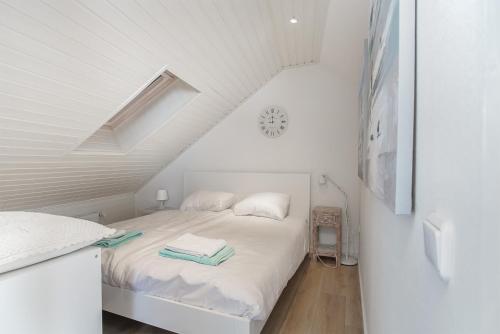 a white bedroom with a bed in a attic at Hello Zeeland - Vakantiehuis Noordstraat 32 in Zoutelande