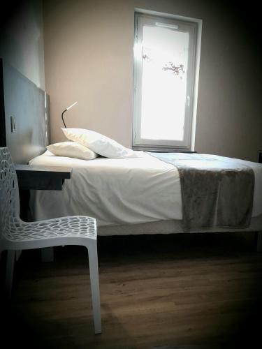 a bedroom with a bed and a chair and a window at le tout va bien in Valence-dʼAgen
