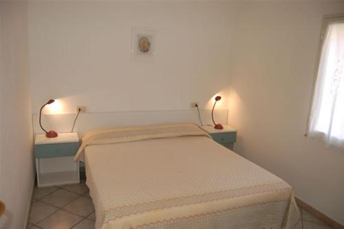 a small bedroom with a bed and two lights on the wall at Residence Villa Franca in Capoliveri