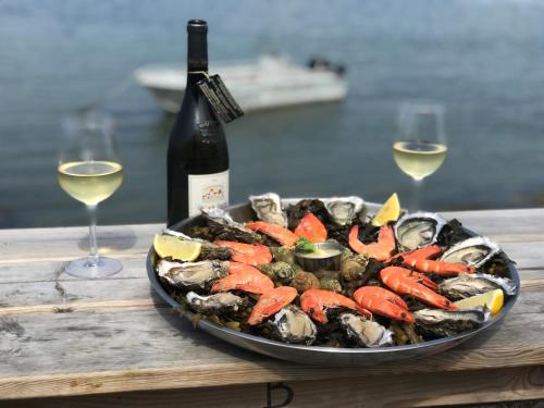 - une assiette de fruits de mer avec une bouteille de vin et des verres à vin dans l'établissement AQUA AURA - LE STANDING AVEC PISCINE, à Saint-Gildas-de-Rhuys