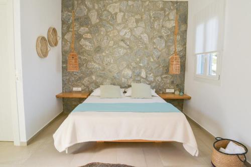 a bedroom with a bed and a stone wall at Hawk Stone in Adamas