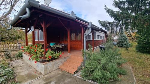 ein Haus mit einer Veranda mit einem Tisch und Blumen in der Unterkunft Bianka vendégház in Berekfürdő