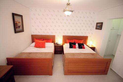two beds in a small room with red pillows at Olympia Hotel in Sarandë