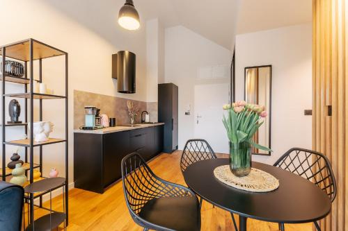 un comedor con una mesa con un jarrón de flores. en Apartament BLACK OAK SurfingBird Dźwirzyno, en Dźwirzyno