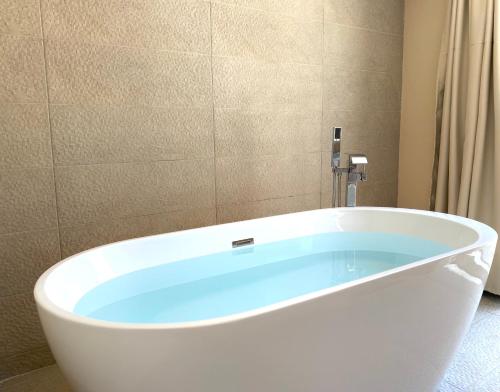 a bath tub with a blue water in a bathroom at Pool Villa Lagonisi 5min from Beach in Koropíon