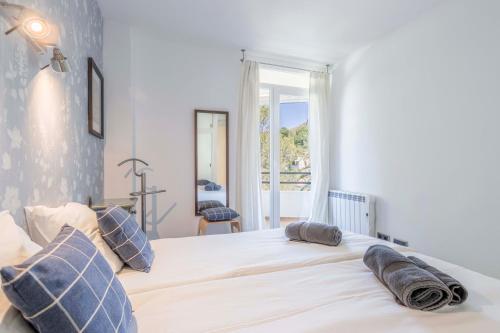 une chambre avec un grand lit blanc avec des oreillers bleus dans l'établissement Lord Jim Pinewalk Apartment, à Port de Pollença