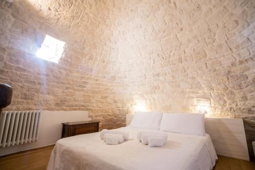 a bedroom with a white bed and a brick wall at Trullo Antica Bellezza in Alberobello