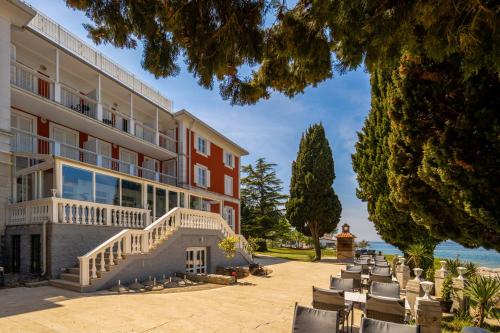a large building with tables and chairs in front of it at Villa Valdepian Apartments in Savudrija