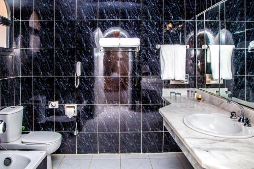 Baño de azulejos negros con aseo y lavamanos en TIME Coral Nuweiba Resort en Nuweiba