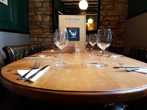 una mesa de madera con copas de vino encima en The Blue Cow en South Witham