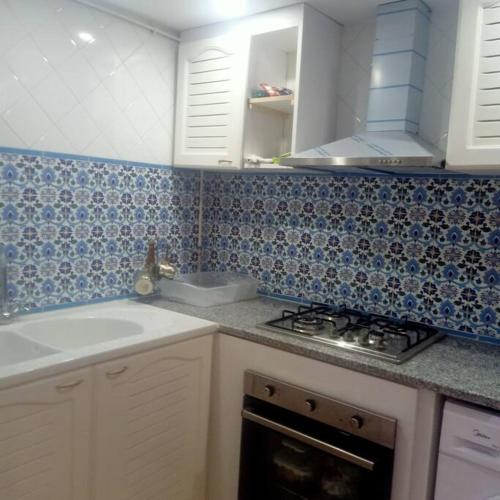a kitchen with blue and white tiles on the wall at Dar Tata in Nabeul