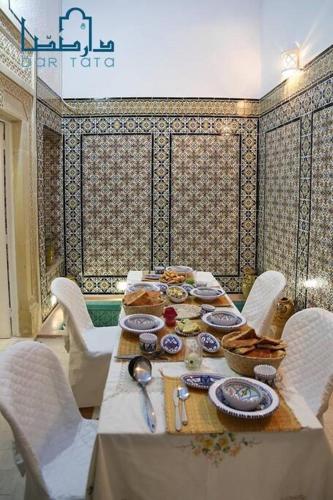 a table with chairs and plates of food on it at Dar Tata in Nabeul