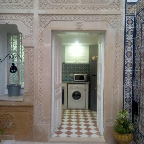 a kitchen with a door open to a kitchen with a washing machine at Dar Tata in Nabeul