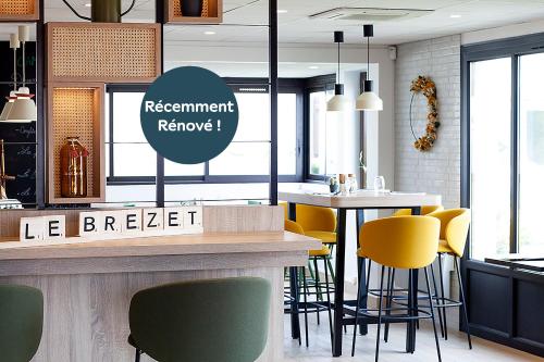 a restaurant with yellow chairs and a counter at Campanile Clermont Ferrand - Le Brezet in Clermont-Ferrand