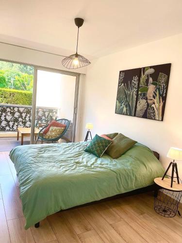- une chambre avec un lit vert et une grande fenêtre dans l'établissement Appartement en résidence avec piscine, cinéma, à Nice