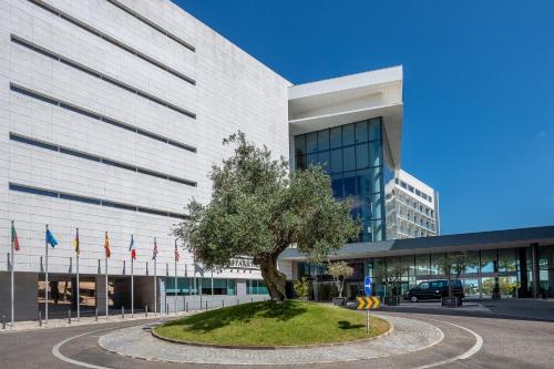 a tree in front of a building with flags at Lagoas Park Hotel in Oeiras