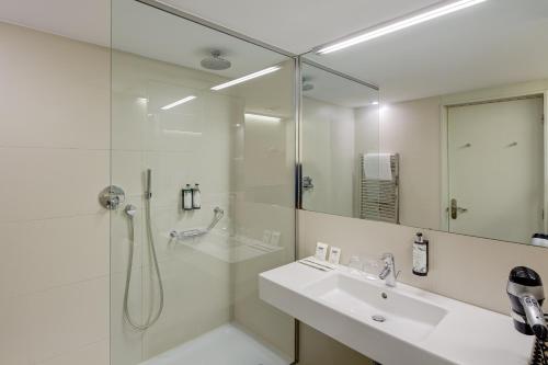 baño blanco con ducha y lavamanos en Sercotel Hotel Rosellon en Barcelona