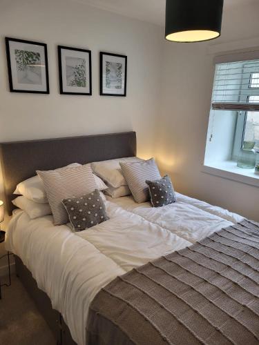 a large bed in a bedroom with two pillows on it at The Bailey - Troon - Coorie Doon Stays in Troon