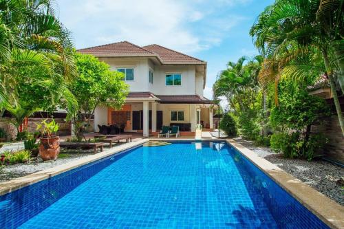 a villa with a swimming pool in front of a house at Captivating 3-Bed Villa in Muang Pattaya in Nong Prue
