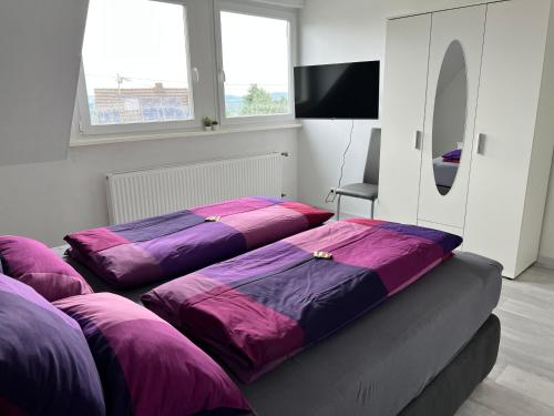 - 2 lits dans une chambre avec des draps violets dans l'établissement Helle moderne Ferienwohnung, Nähe Koblenz am Rhein, à Weitersburg