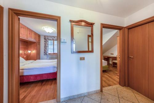 pasillo que conduce a un dormitorio con cama y espejo en Ciasa Sommavilla Calendula, en Vigo di Fassa
