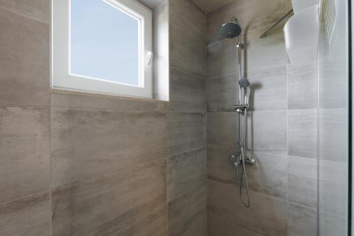 a bathroom with a shower with a window at Mythos Modern Loft in Dassia