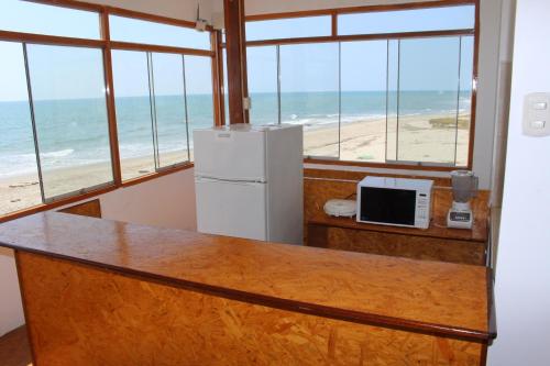 a room with a counter with a refrigerator and the beach at Casa de Playa Alarcon - Huacura in Bocapán