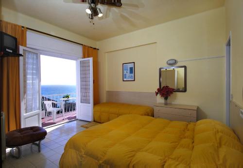 a bedroom with a yellow bed and a balcony at Hotel Nettuno in Diano Marina