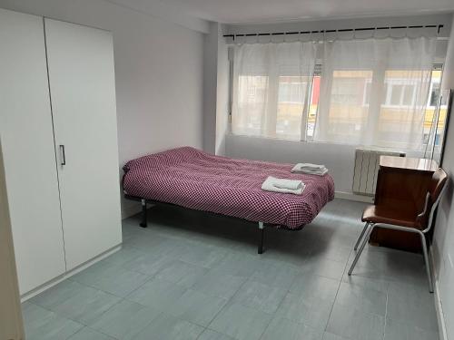 - une chambre avec un lit, une chaise et une fenêtre dans l'établissement Loft en Torrelavega, à Torrelavega