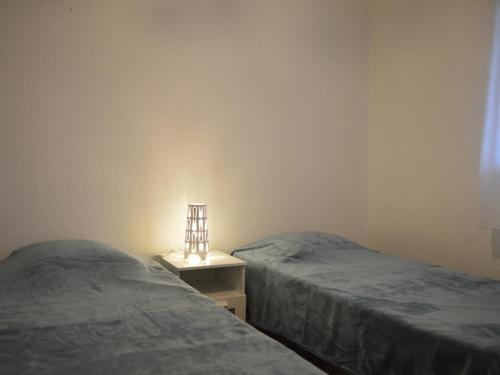 - 2 lits dans une chambre avec une lampe sur une table de chevet dans l'établissement Appartement à Sainte-Maxime: 3 Pièces, Terrasse, Piscine, Clim, Proche Plage - FR-1-226-340, à Sainte-Maxime