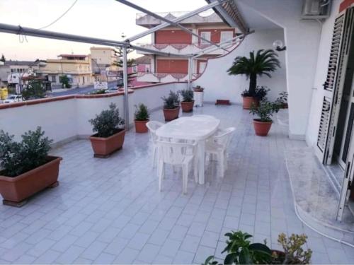 een witte tafel en stoelen op een patio met planten bij House with sea view/Casa con terrazzo vista mare in Siderno Marina