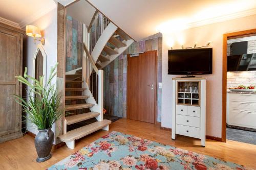 a living room with a staircase and a tv at Landhaus Wremer Deel in Wremen