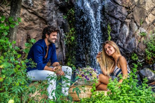 a man and woman sitting in front of a waterfall at Grande Hotel das Caldas da Felgueira in Caldas da Felgueira
