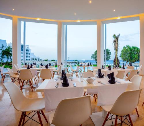 a restaurant with white tables and chairs and windows at Le Sultan in Hammamet