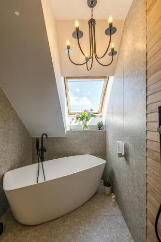 a large white bath tub in a bathroom with a window at Urban Oasis Apartments with Parking in Bucharest