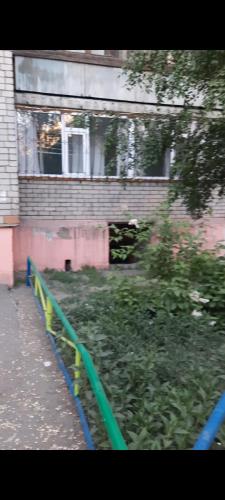 a green fence in front of a building at Уютная квартира in Semey