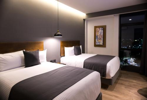 グアダラハラにあるGumont Guadalajara López Mateos - Minervaのベッド2台と窓が備わるホテルルームです。
