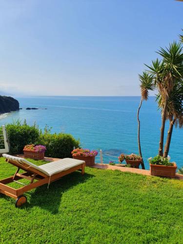 un banco sentado en el césped cerca del océano en Casa Guido, en Cittadella del Capo