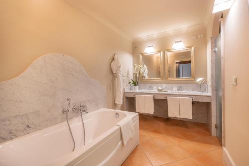 a white bathroom with two sinks and a tub at Almar Giardino di Costanza Resort & Spa in Mazara del Vallo