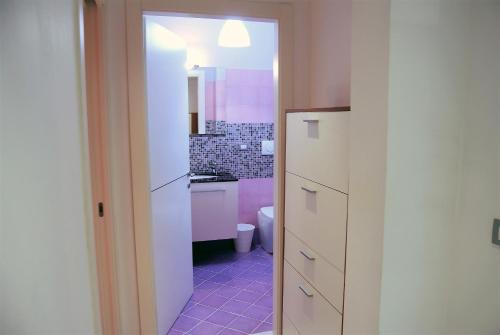 a bathroom with a pink tiled floor and white cabinets at Costa del Molo - Casa e Lavoro in Vado Ligure